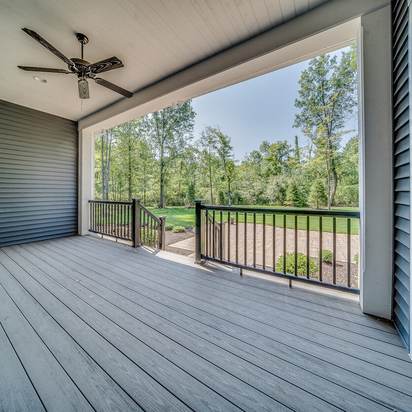 Trex decking with black metal railing and ceiling fan under covering
